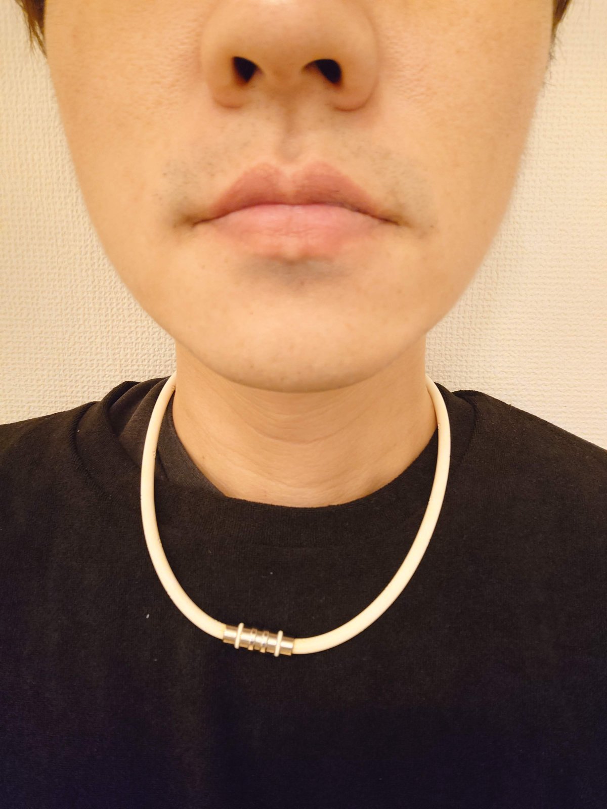 顔の下半分と白いネックレスの写真